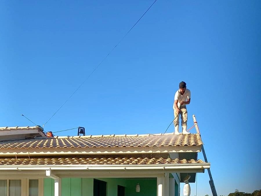 Paulo em cima do telhado de uma casa realizando lavação